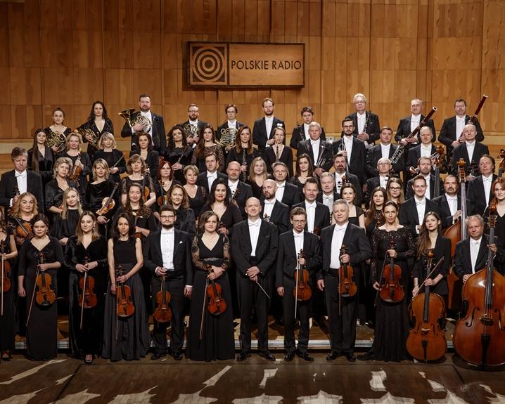 Orkiestra Polskiego Radia, muzycy ubrani w czarne sukienk i fraki stoją w czterech rzędach na estradzie 