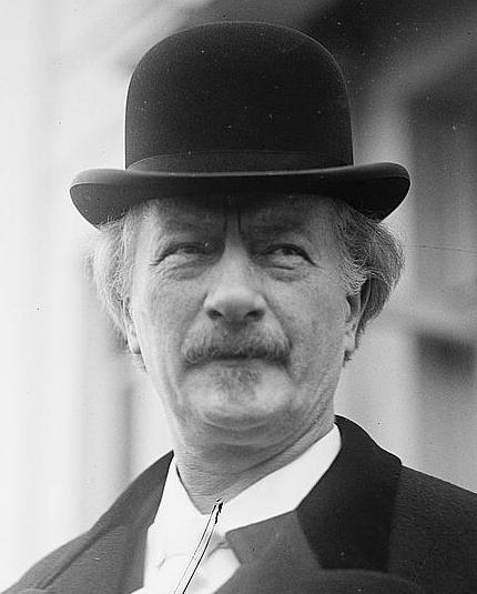 Kompozytor Ignacy Jan Paderewski w siwych włosach i czarnym kapeluszu patrzy w dal